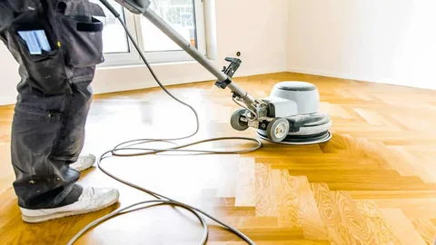 Professional using a dustless floor sanding machine in a residential living space.