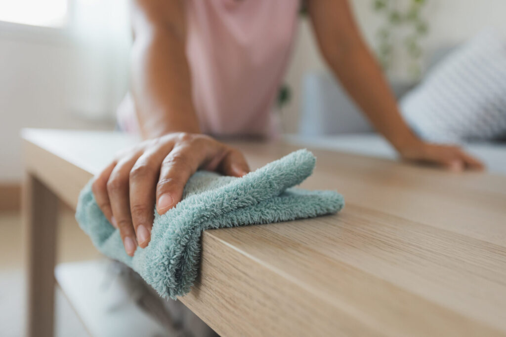 A hand blotting water from wood flooring with a soft microfiber cloth